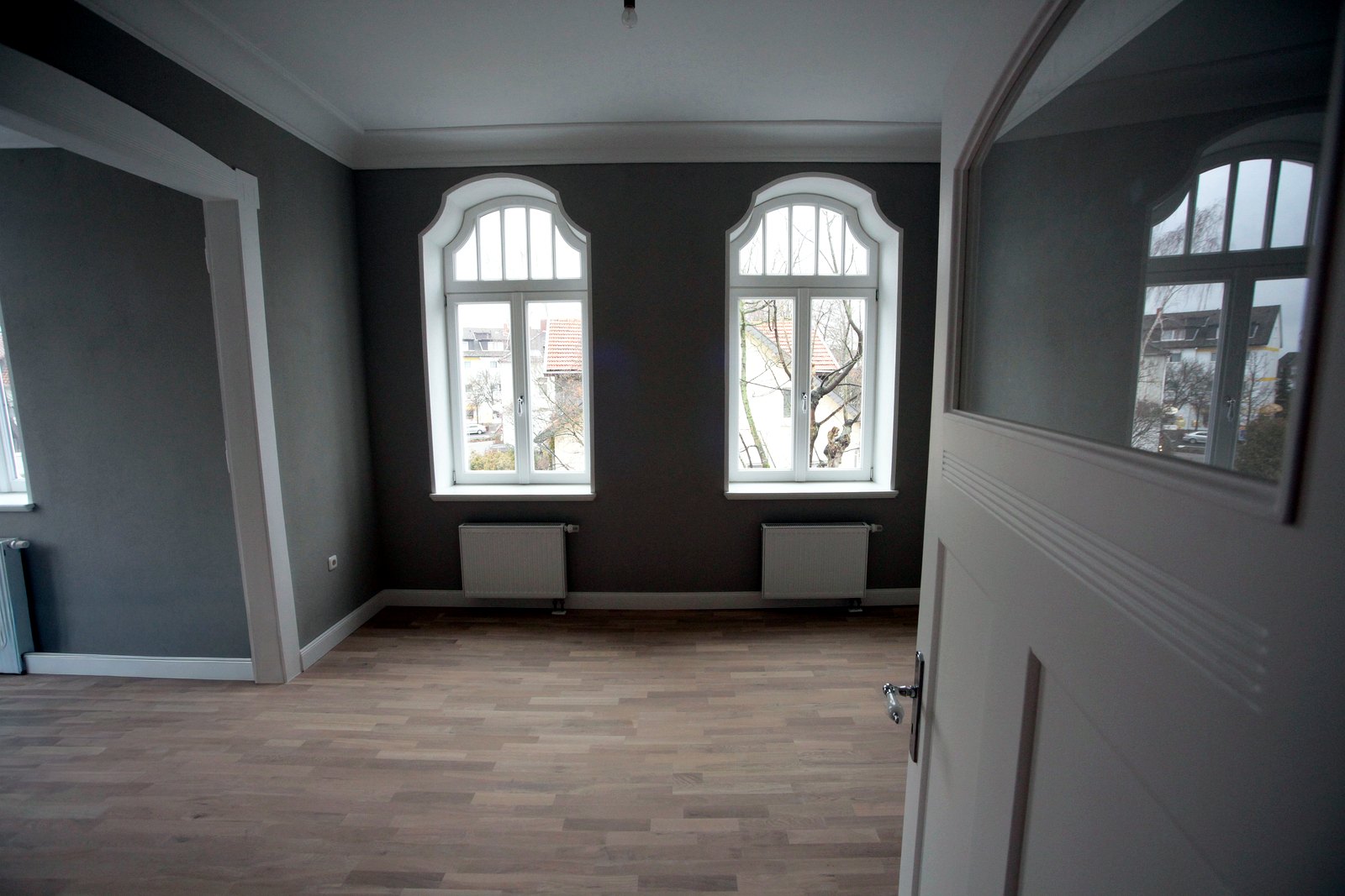 Heller Wohnraum mit Rundbogenfenstern in der sanierten Altbauwohnung Weststraße, Bad Oeynhausen