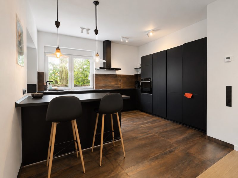 Moderne schwarze Einbauküche mit Kochinsel und Barhockern im kernsanierten Brunnenmeisterhaus in Bad Oeynhausen