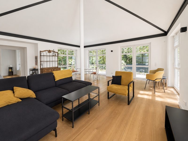 Offener Wohnraum mit sichtbaren Balken, Eichenparkett und Terrassentüren zum Garten im Altbau im Sielpark